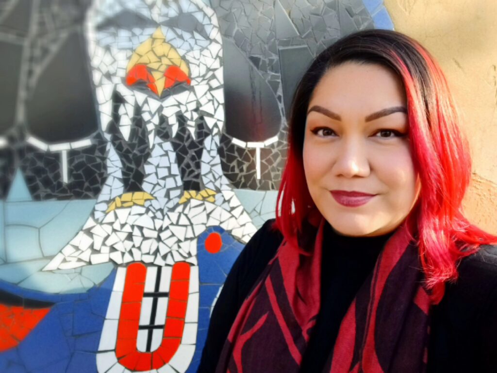 Crystal Harper, an Indigenous Patient Navigator at BC Cancer – Vancouver, stands in front of a mural created by her late father who she lost to liver cancer in 2021.